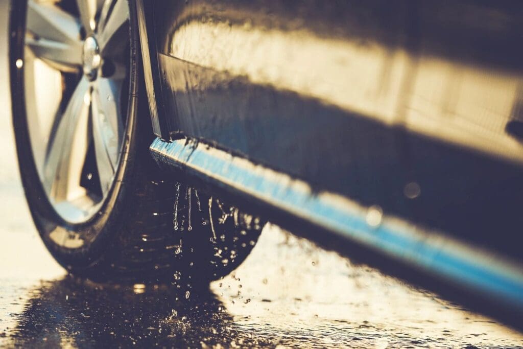 Car wheel splashing water on road.
